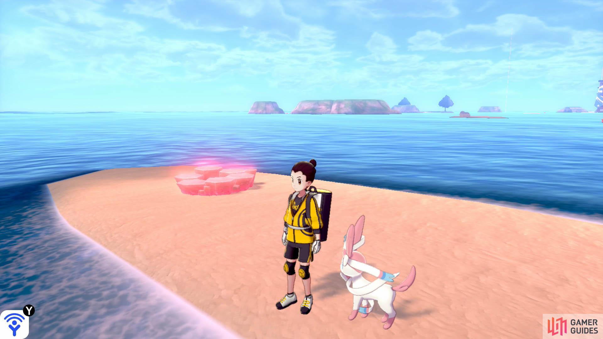 To the right of the string of Pokémon Dens (with your back facing the Tower of Waters), there’s a long, sandy island. This den is located towards the tip nearest to the tower.